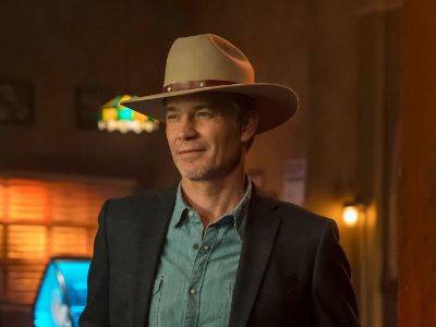 Timothy Olyphant is wearing a cowboy hat, a suit. and a denim shirt.